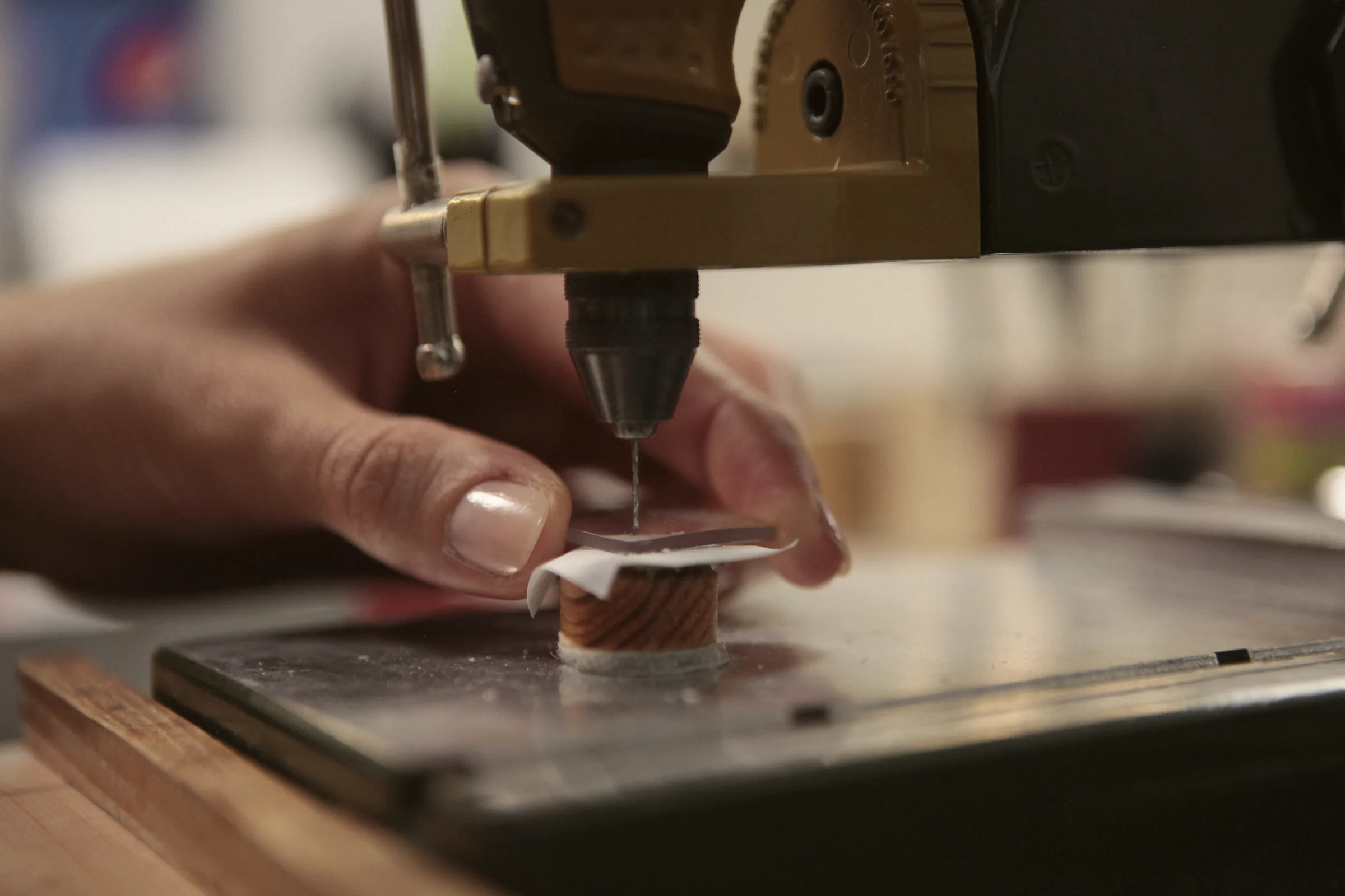 Ein Brillenglas wird in der Werkstatt mit einer feinen Bohrmaschine für eine randlose Brille gebohrt.